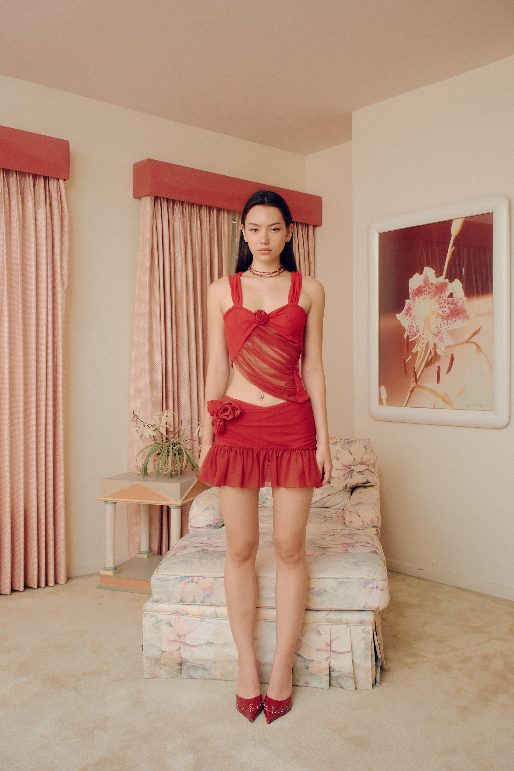 The Red Talk mesh flower asymmetric top adds an effortless yet bold and iconic touch to your wardrobe. The center rosette decorations provide an elegant focal point.