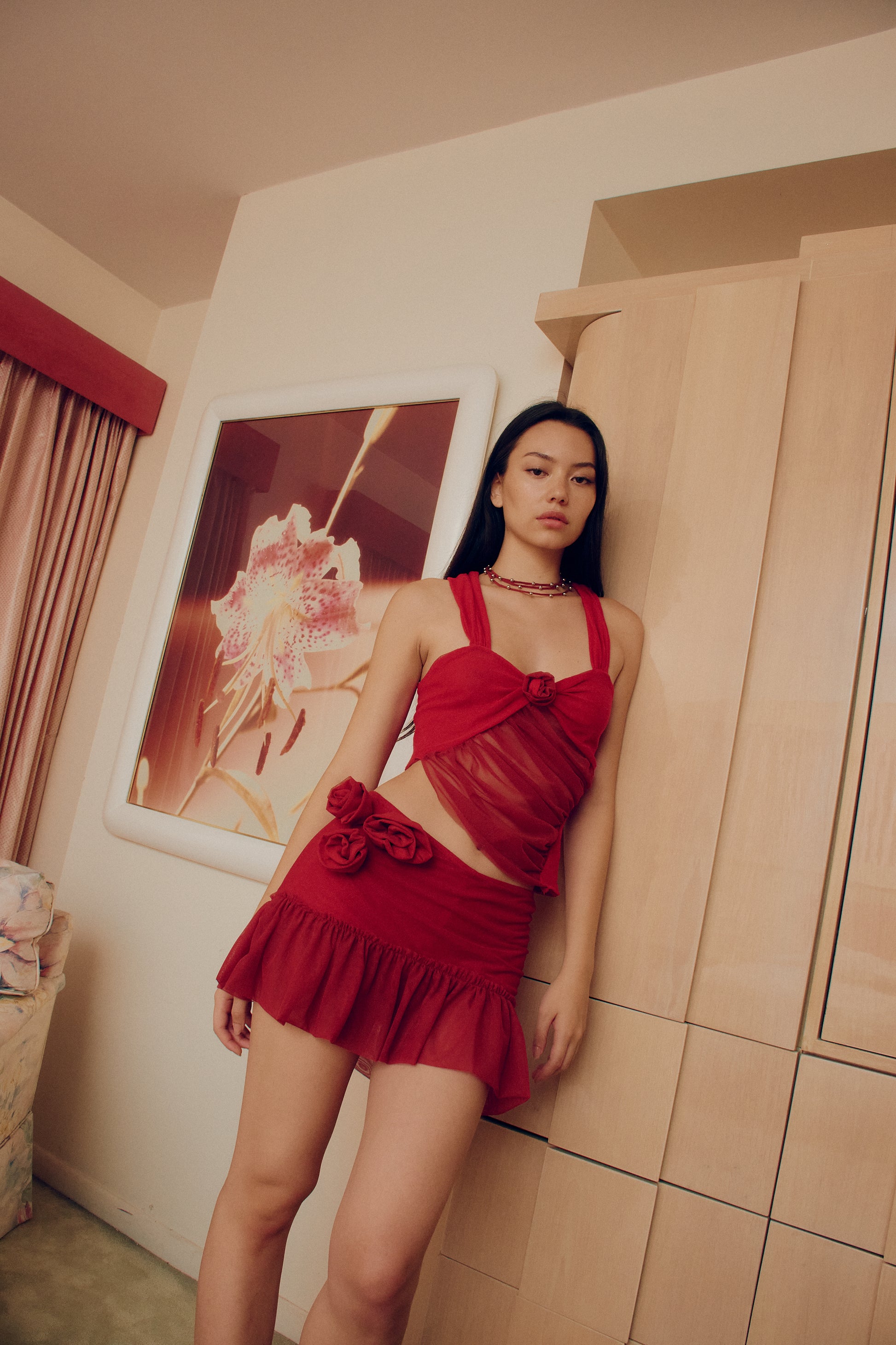 The Red Talk Flower Skirt Red features rosette decorations on the side and a mesh knit design for a chic and comfortable look.