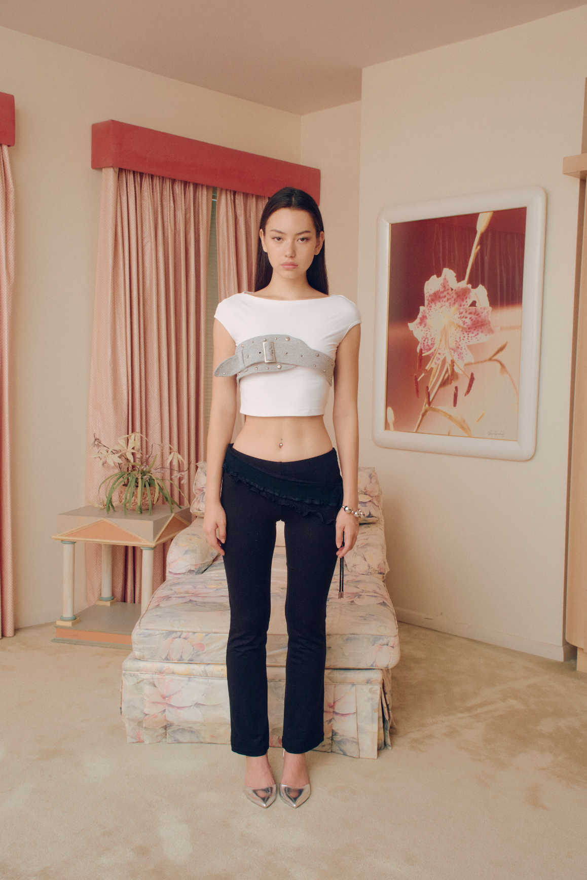 This white crop top exudes effortless sophistication with a modern edge. Made from a soft, stretchy fabric, it offers a flawless, comfortable fit. The standout feature is a sleek gray studded belt encircling the bust, adding a subtle touch of boldness. The adjustable belt ensures a perfect fit, elevating the silhouette with a refined, contemporary edge. Versatile and chic, pair it with high-waisted trousers, skirts, or a blazer for an understated, elegant look. A must-have for those who dare to stand out.